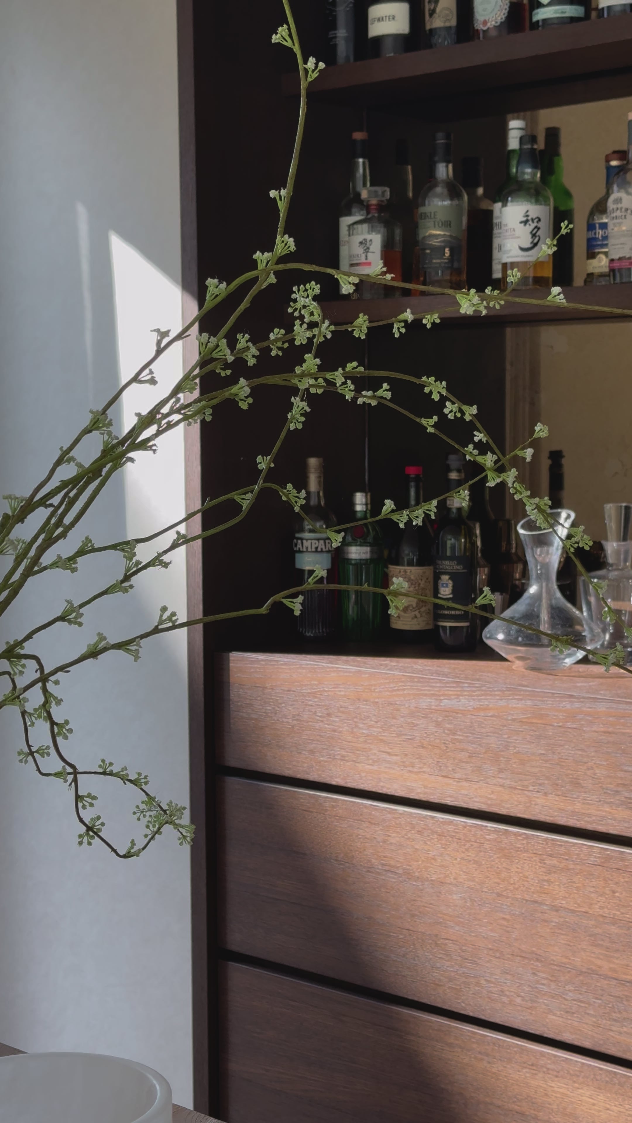 Lange Spirea kunsttak gestyled in een hoge vaas – natuurlijke interieurdecoratie